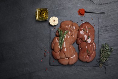 Photo of Fresh raw kidneys with seasonings on black table, flat lay. Space for text