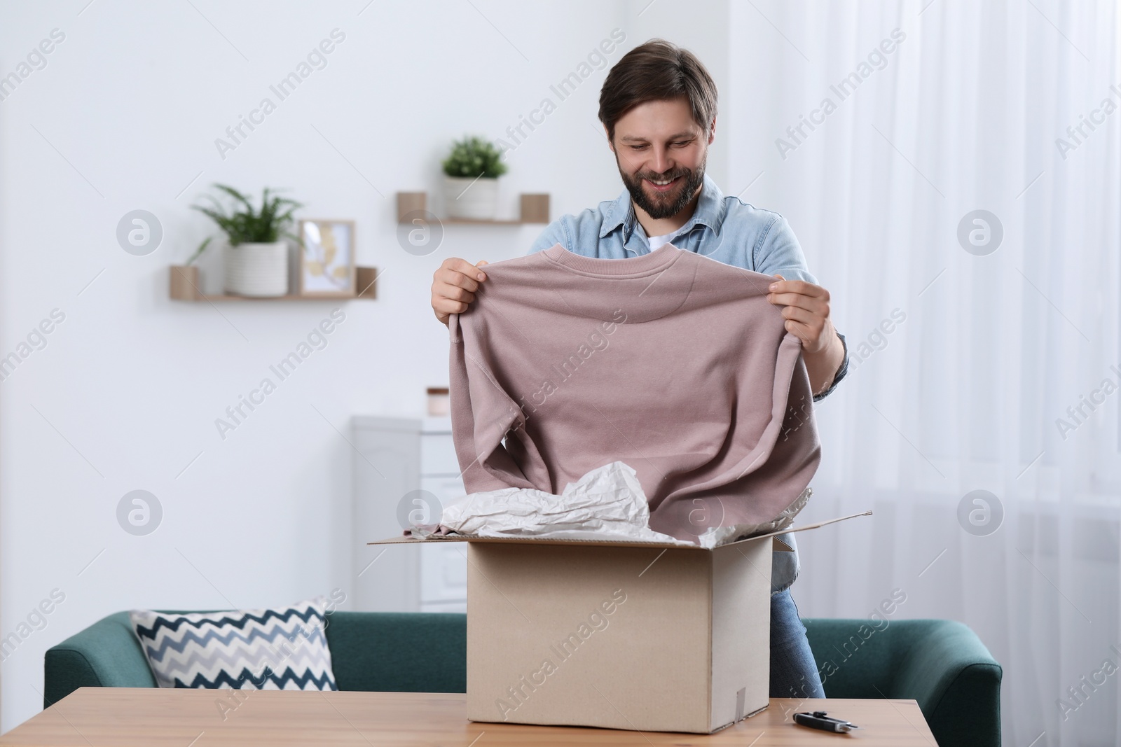 Photo of Happy man with parcel at home. Internet shopping