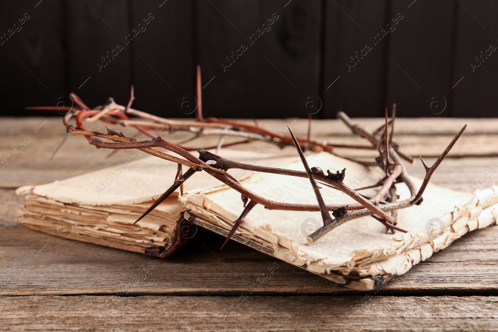 Photo of Crown of thorns and Bible on wooden table, closeup