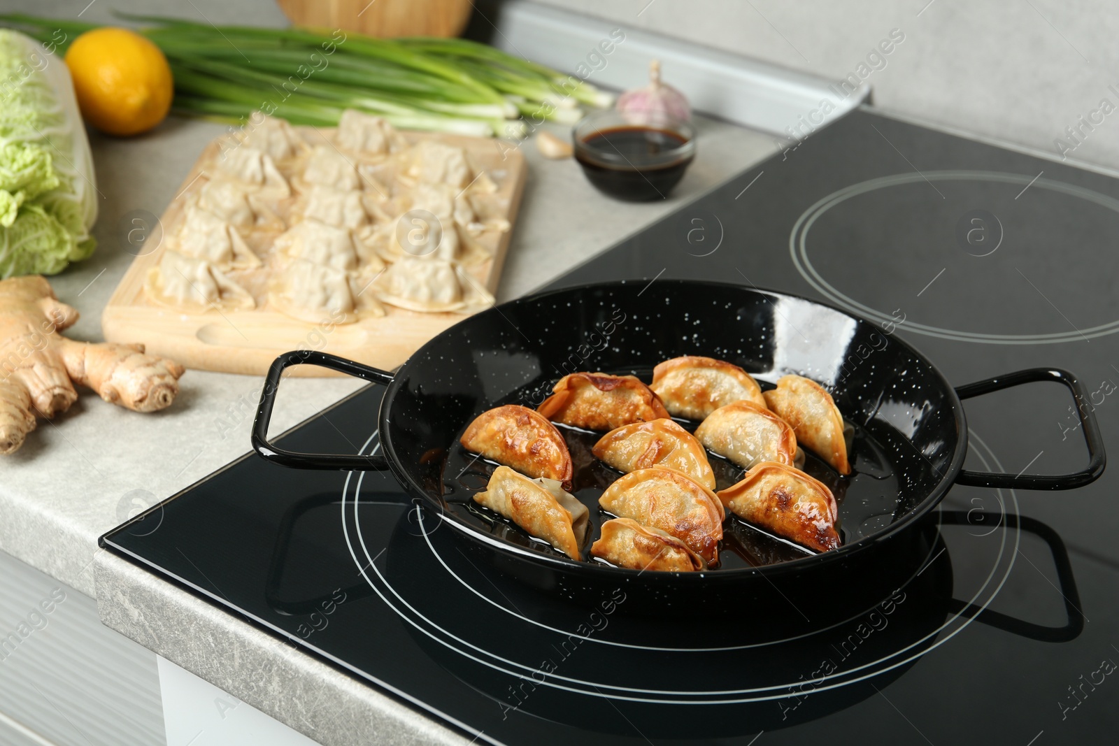 Photo of Cooking gyoza on frying pan with hot oil in kitchen