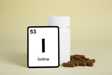 Photo of Card with iodine element, jar and pills on beige background