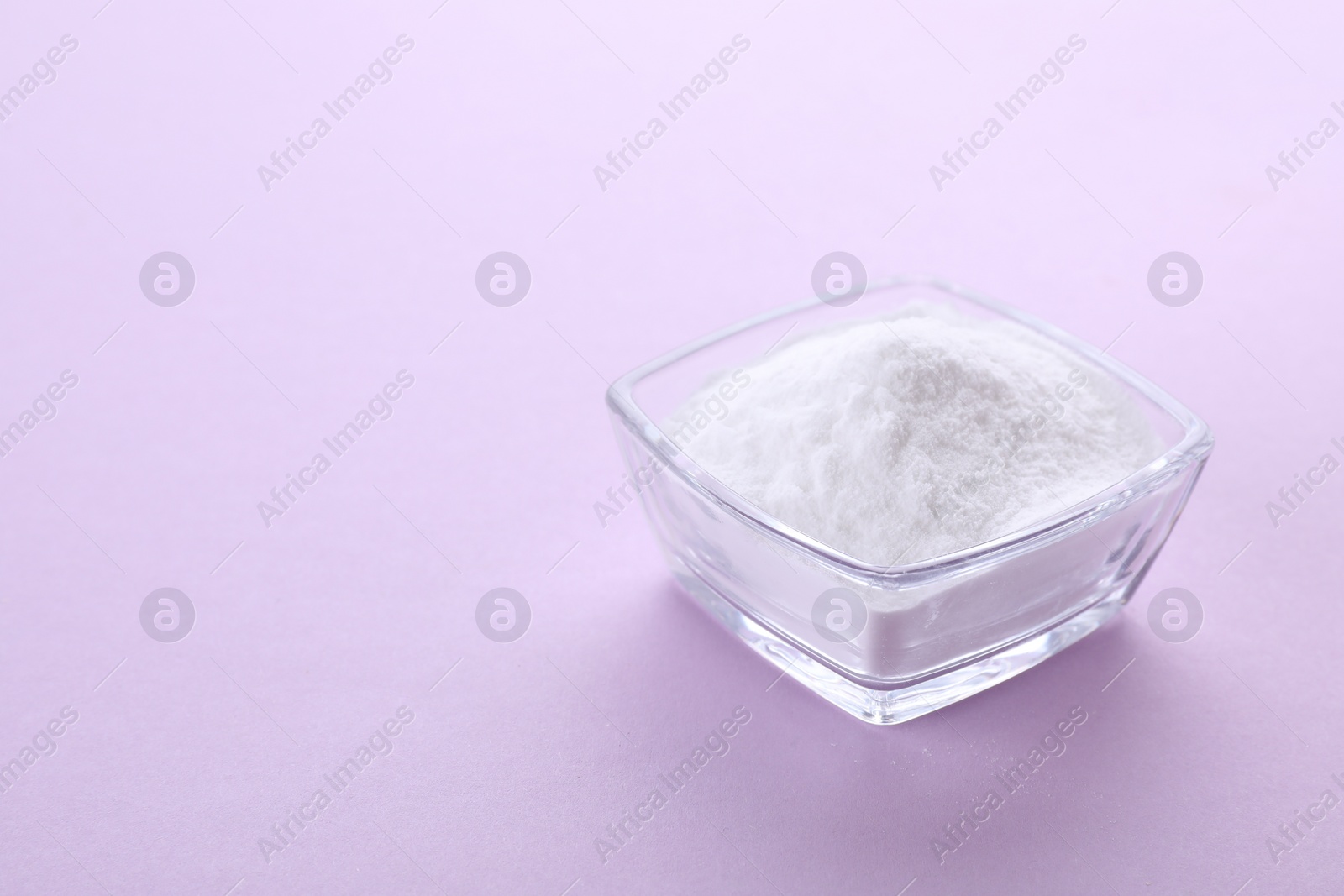 Photo of Bowl of sweet powdered fructose on light purple background. Space for text