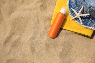 Sunscreen, panama hat, starfish and towel on sandy beach, top view and space for text. Sun protection