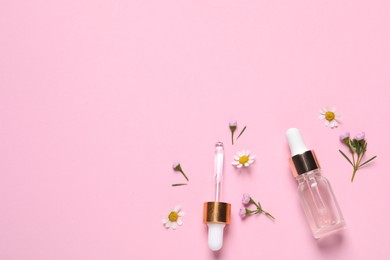 Photo of Bottle of cosmetic serum, pipette and beautiful flowers on pink background, flat lay. Space for text