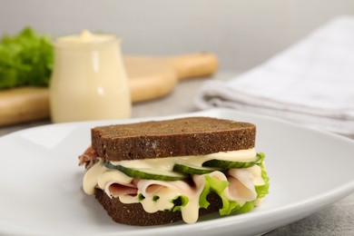Photo of Delicious sandwich with vegetables, ham and mayonnaise on grey table, closeup