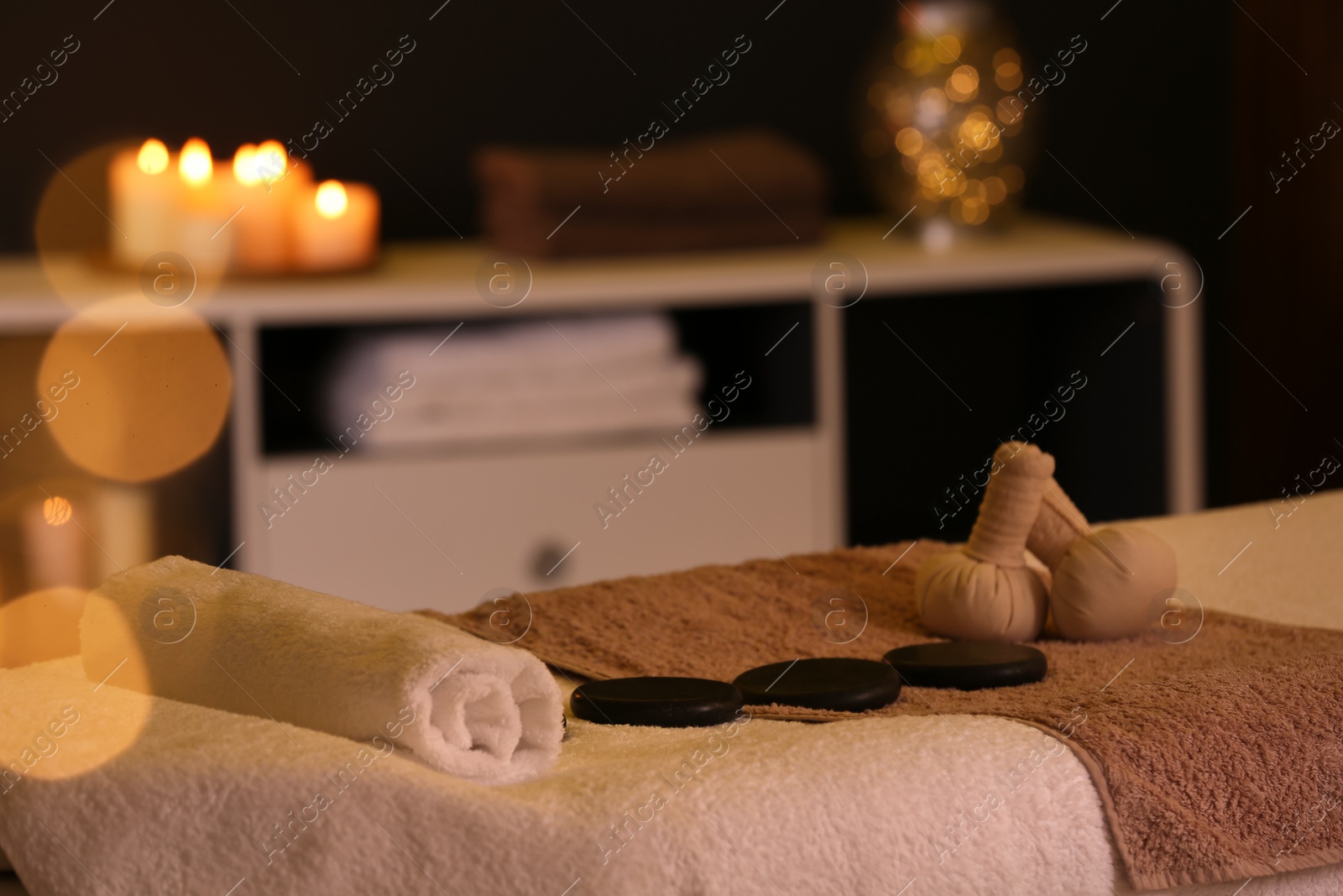 Photo of Herbal compresses and stones on massage table in spa salon