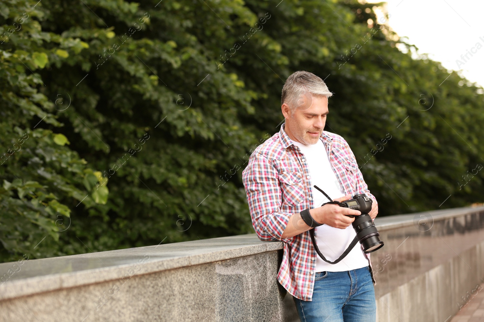 Photo of Handsome mature man with professional camera outdoors. Space for text