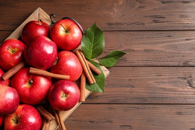 Fresh apples and cinnamon sticks on wooden table, top view