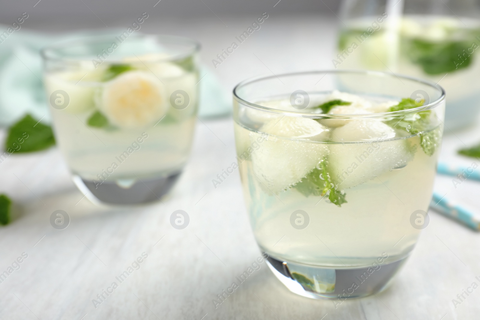 Photo of Glass with tasty melon ball drink on light table