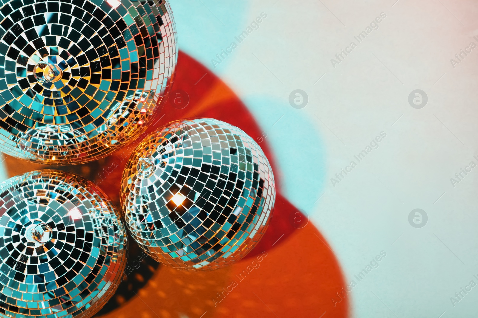Photo of Bright shiny disco balls on color background, top view. Space for text