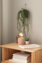 Photo of Stylish lamp and decor on wooden nightstand in room