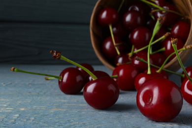 Photo of Delicious ripe sweet cherries on grey wooden table, closeup