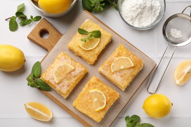 Photo of Tasty lemon bars and mint on white tiled table, flat lay