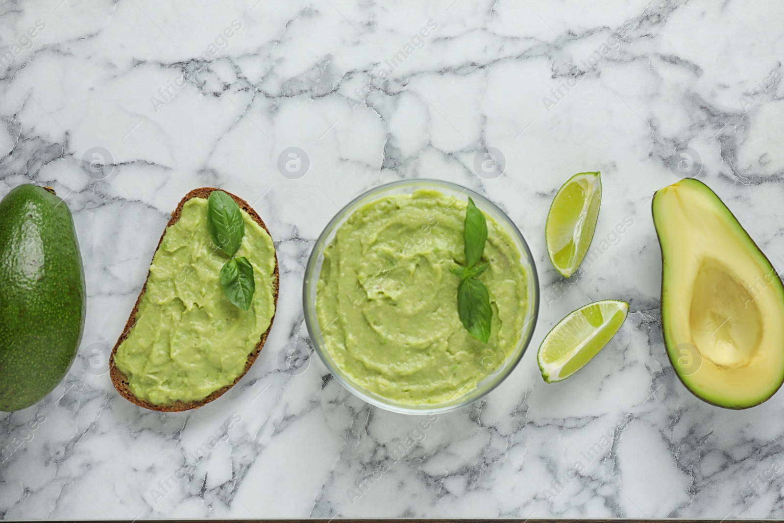 Photo of Flat lay composition with guacamole, sandwich and avocados on white marble table