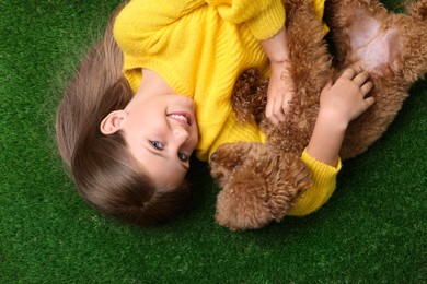 Little child with cute puppy on green grass, top view. Lovely pet