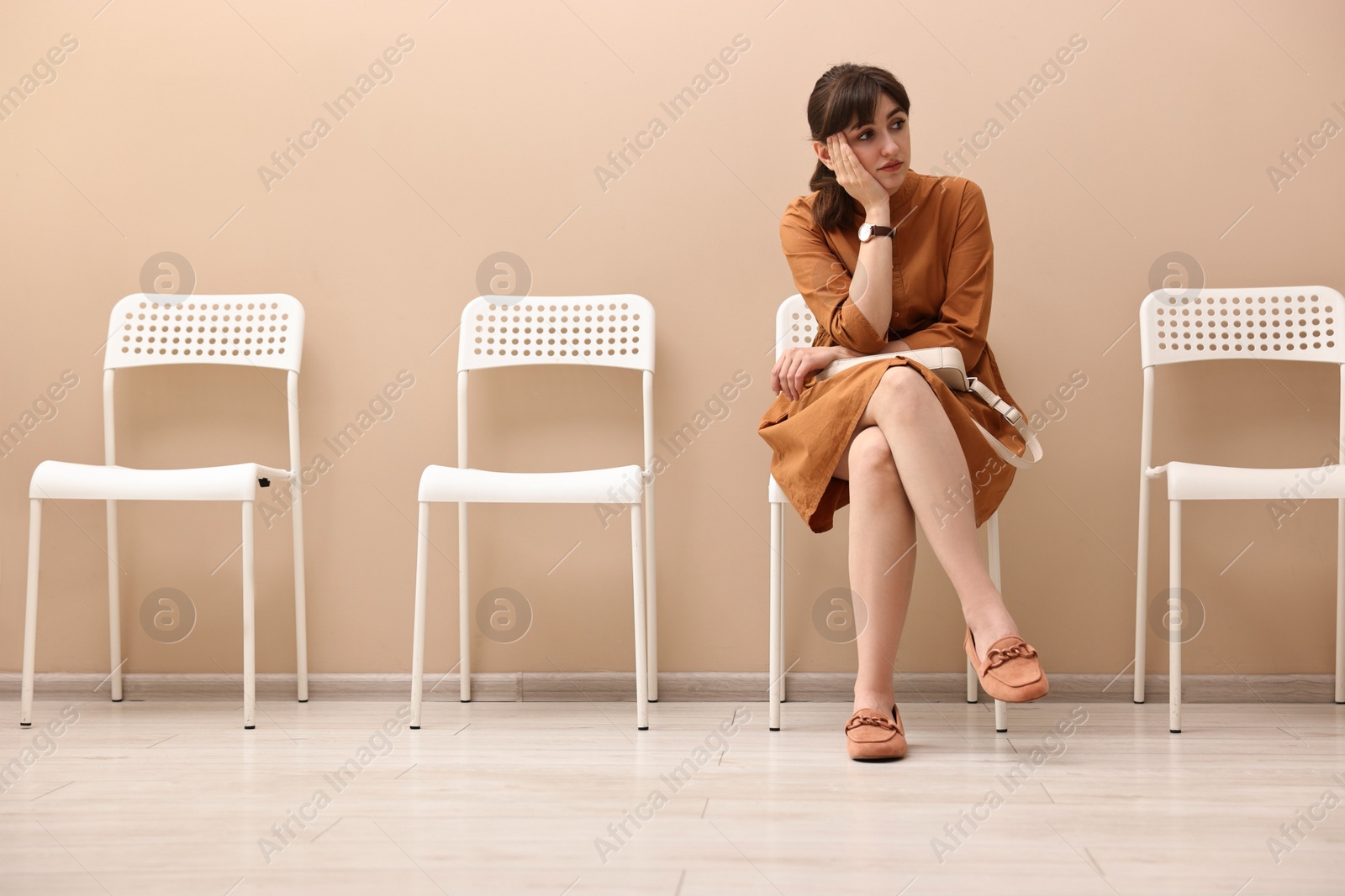 Photo of Woman sitting on chair and waiting for appointment indoors