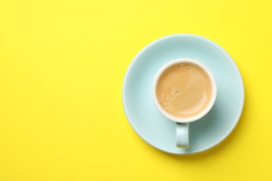 Photo of Aromatic coffee in cup on yellow background, top view. Space for text