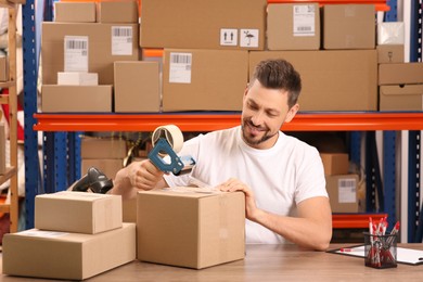 Photo of Post office worker packing parcel at counter indoors