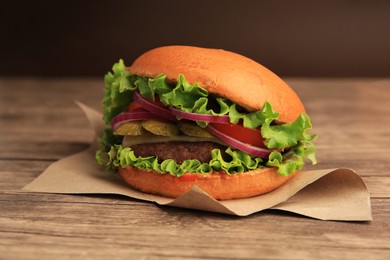 Photo of One tasty burger with vegetables, patty and lettuce on wooden table