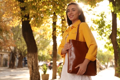 Photo of Young woman with stylish shopper bag outdoors. Space for text