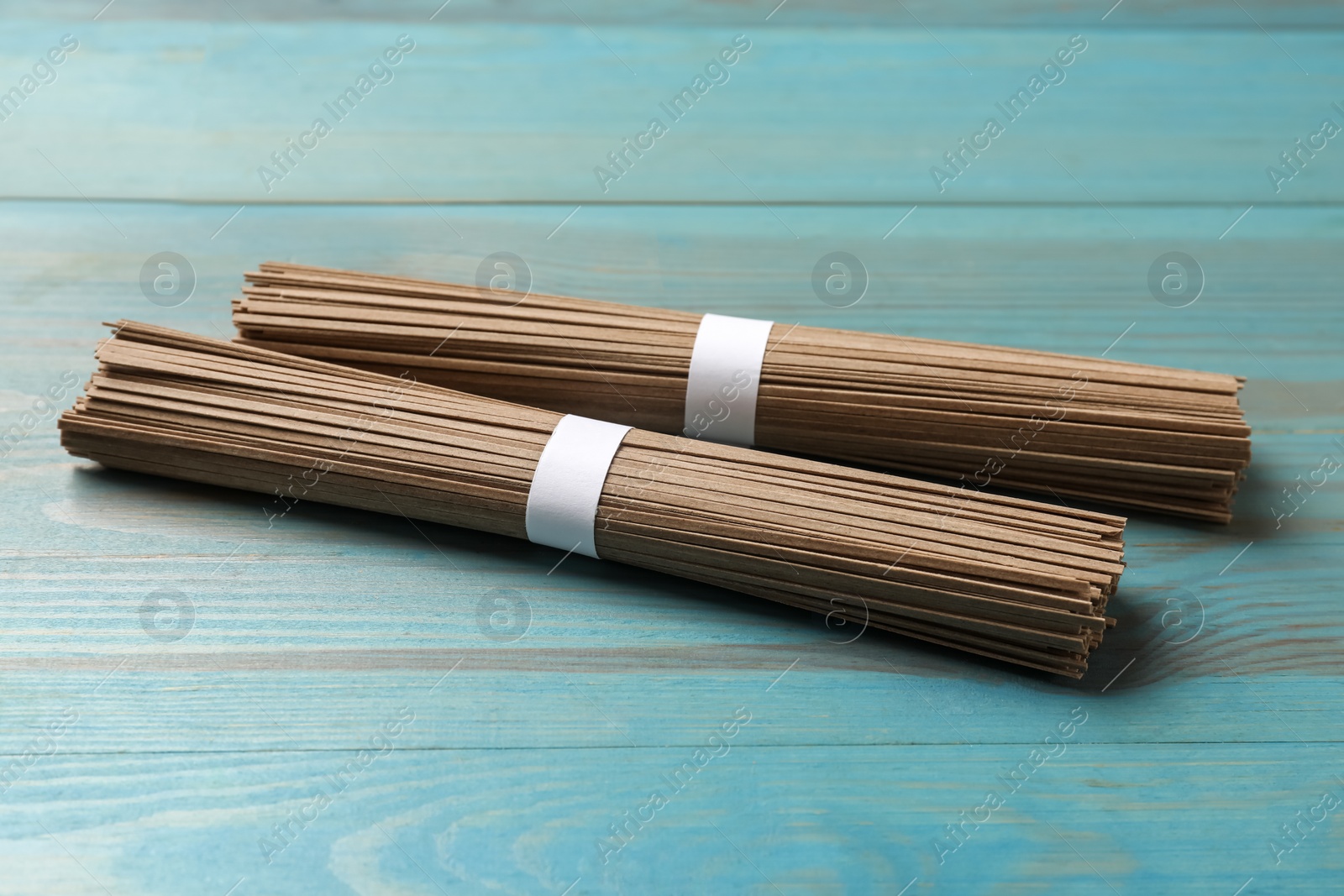 Photo of Uncooked buckwheat noodles (soba) on light blue wooden table