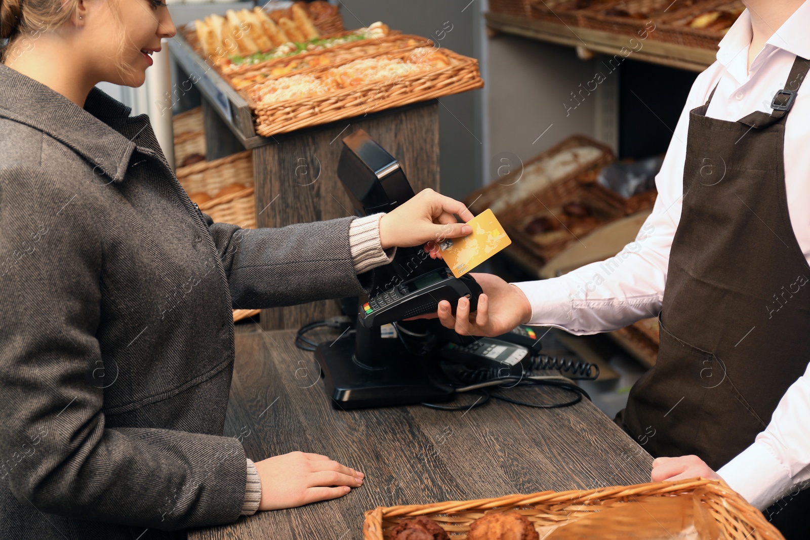 Photo of Woman with credit card using payment terminal at shop