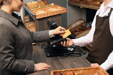 Woman with credit card using payment terminal at shop