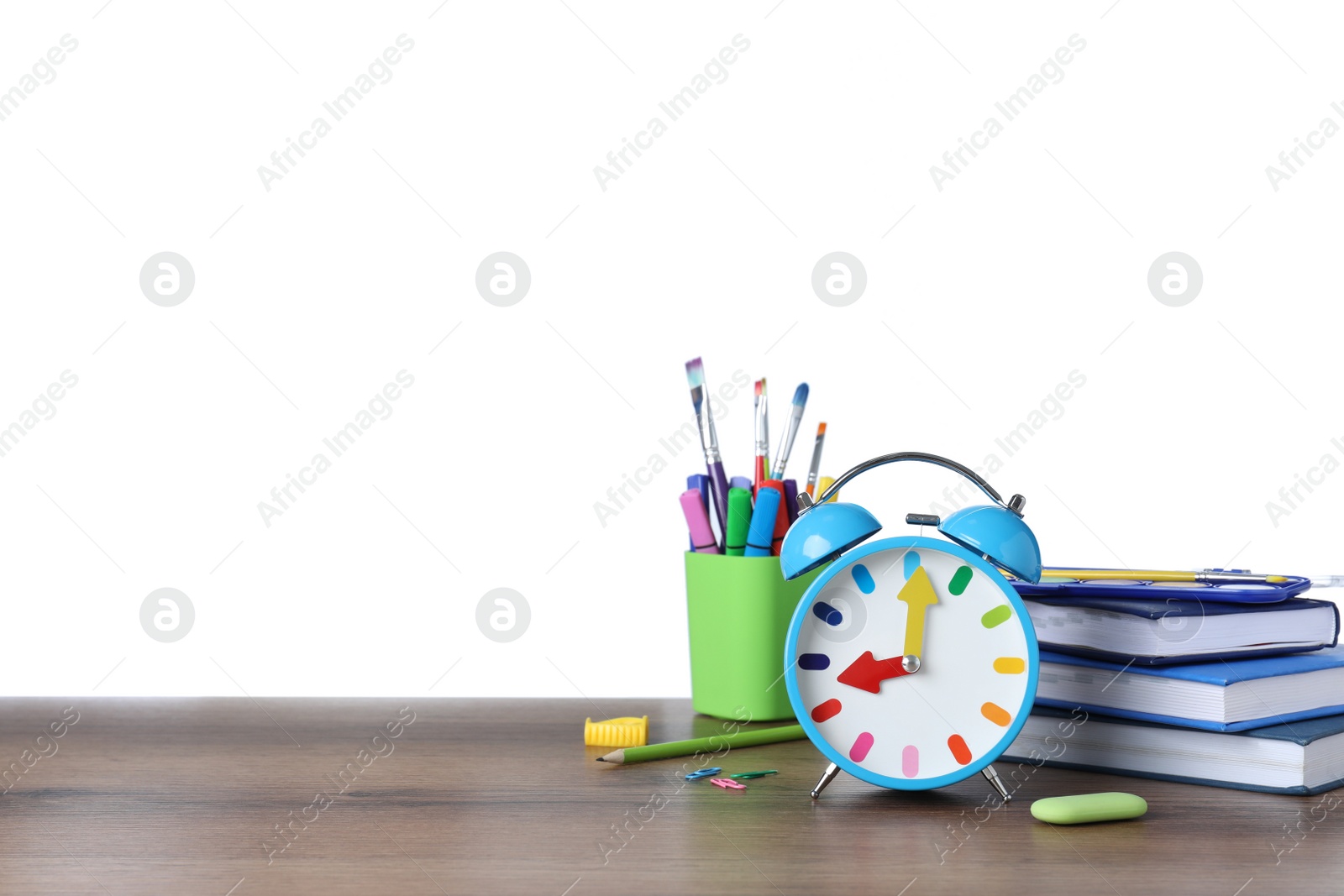 Photo of Light blue alarm clock and different stationery on wooden table against white background, space for text. School time