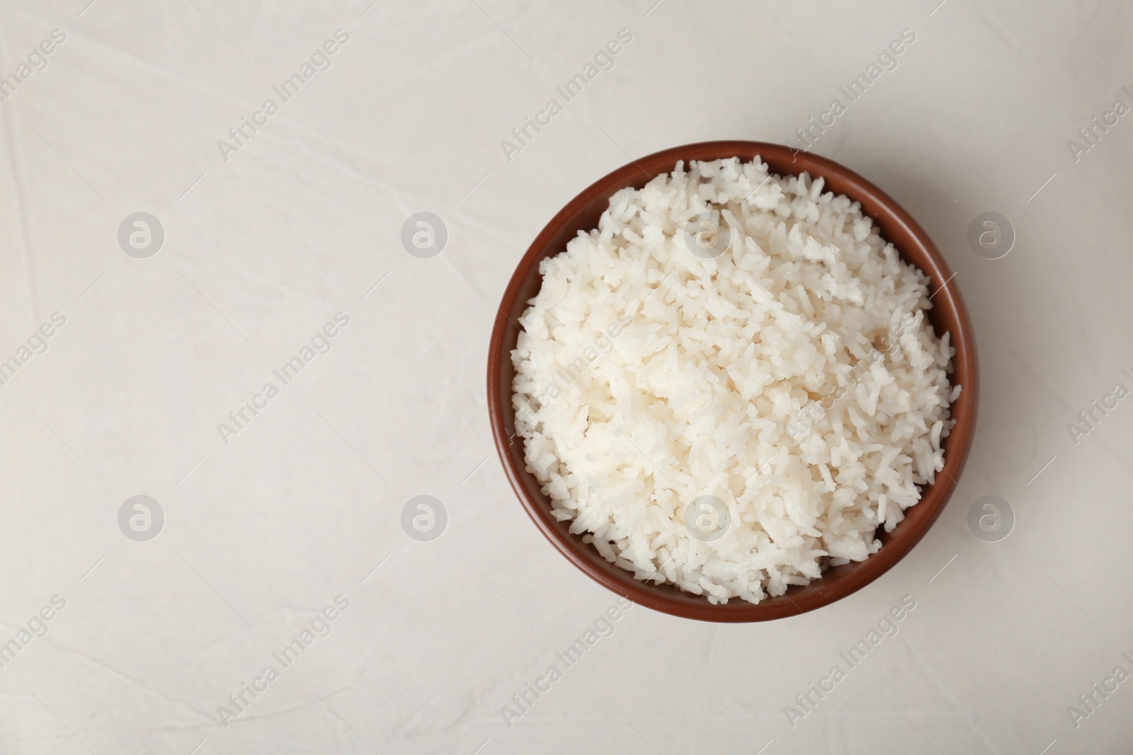 Photo of Bowl of boiled rice on light background, top view with space for text