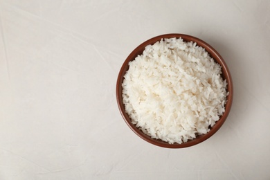 Photo of Bowl of boiled rice on light background, top view with space for text