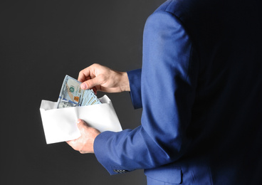 Photo of Man with bribe money on black background, closeup