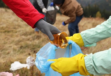 Photo of People with trash bag collecting garbage in nature, closeup