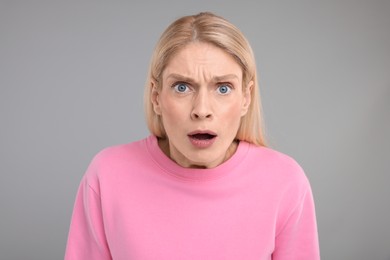 Photo of Portrait of surprised woman on grey background