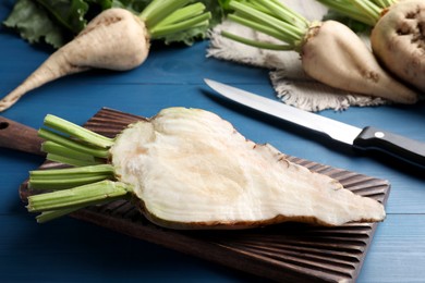 Whole and cut sugar beets on blue wooden table