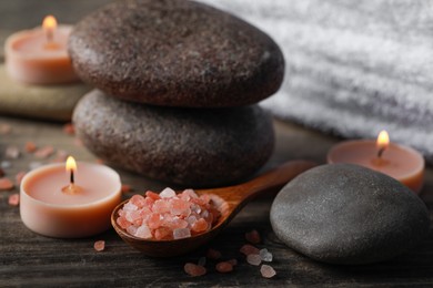 Beautiful composition with spa stones and burning candles on wooden table, closeup