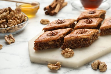 Photo of Delicious honey baklava with walnuts on served white marble table, closeup