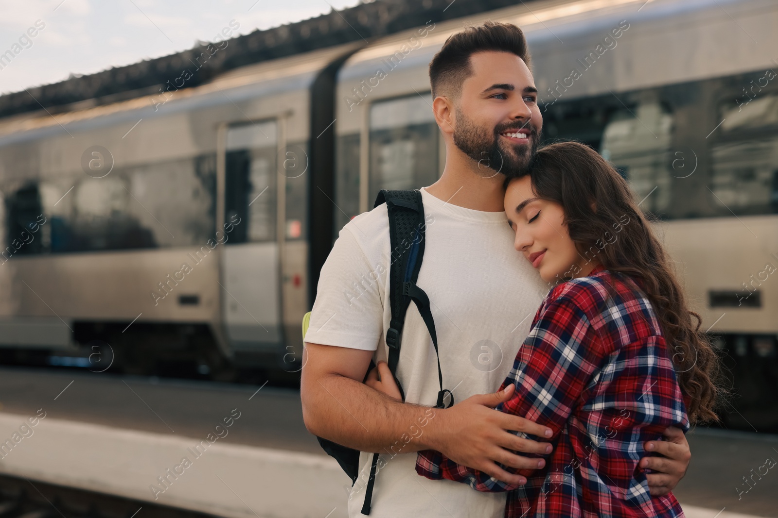 Photo of Long-distance relationship. Beautiful couple hugging on platform of railway station, space for text