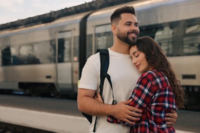 Photo of Long-distance relationship. Beautiful couple hugging on platform of railway station, space for text