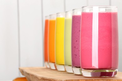 Many different tasty smoothies against white wooden background, space for text