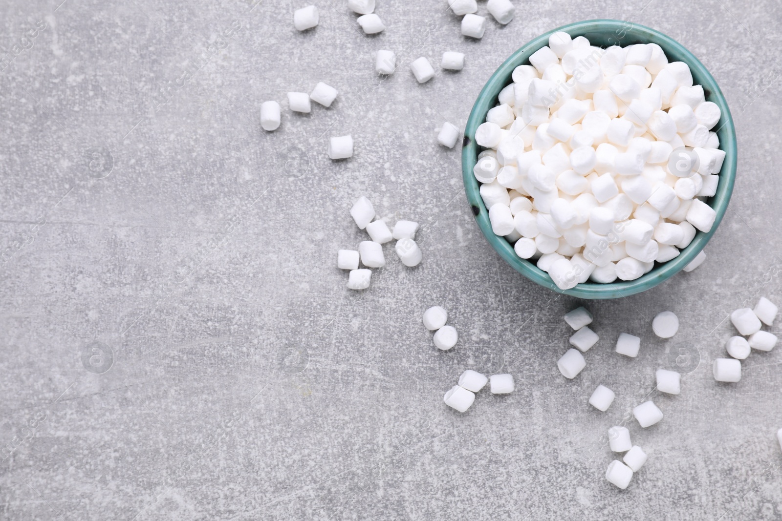 Photo of Bowl with delicious marshmallows on light gray background, flat lay. Space for text