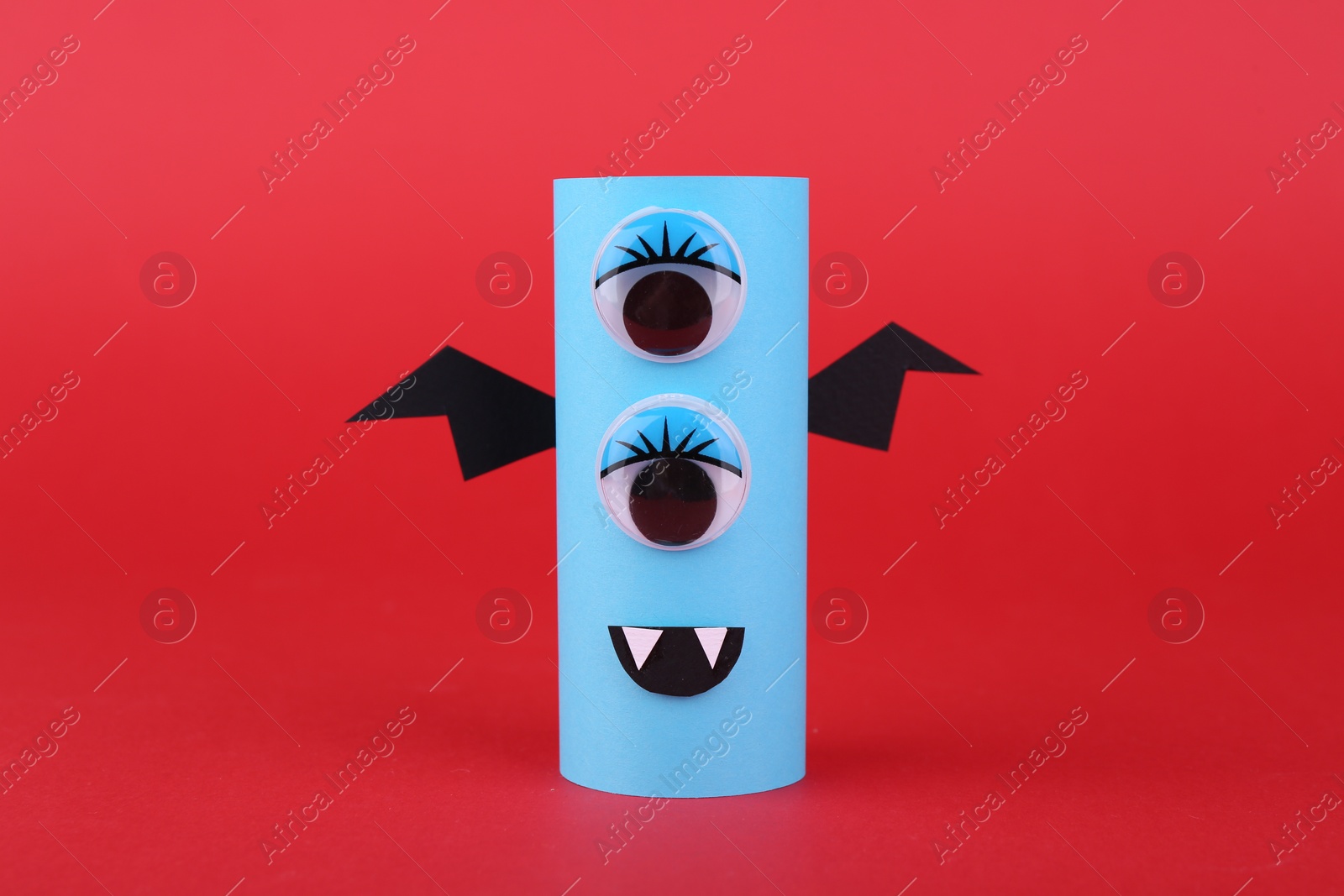 Photo of Spooky paper monster on red background. Handmade Halloween decoration