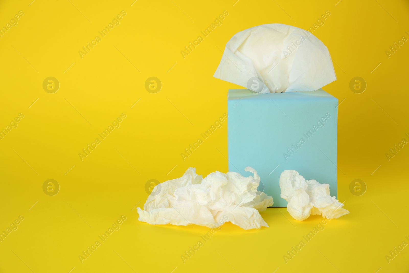 Photo of Used paper tissues and box on yellow background. Space for text