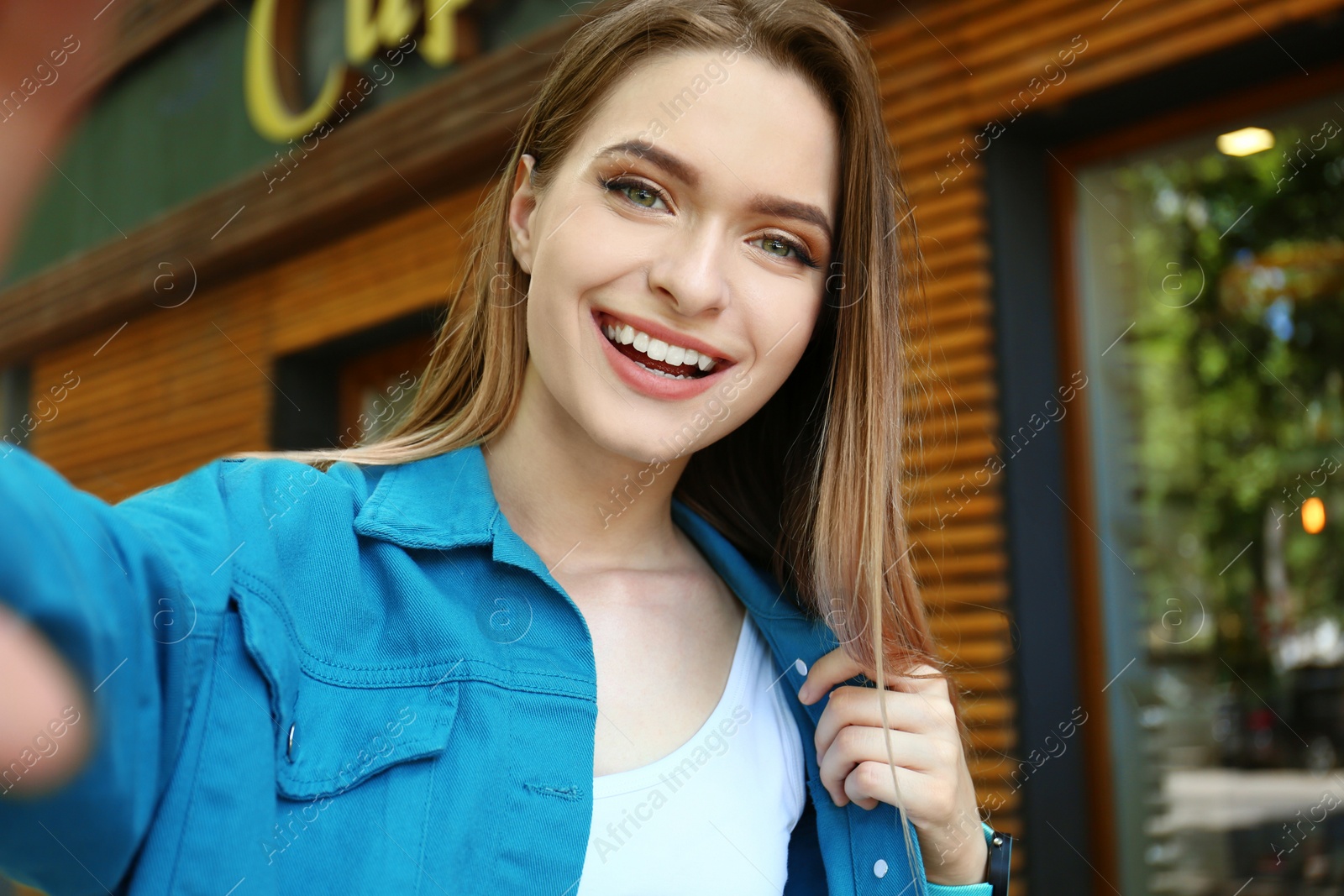 Photo of Happy young woman taking selfie on city street