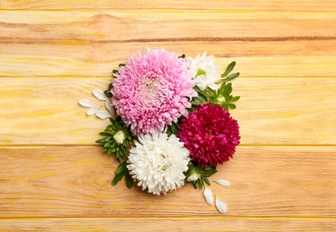 Photo of Beautiful asters on wooden background, flat lay. Autumn flowers