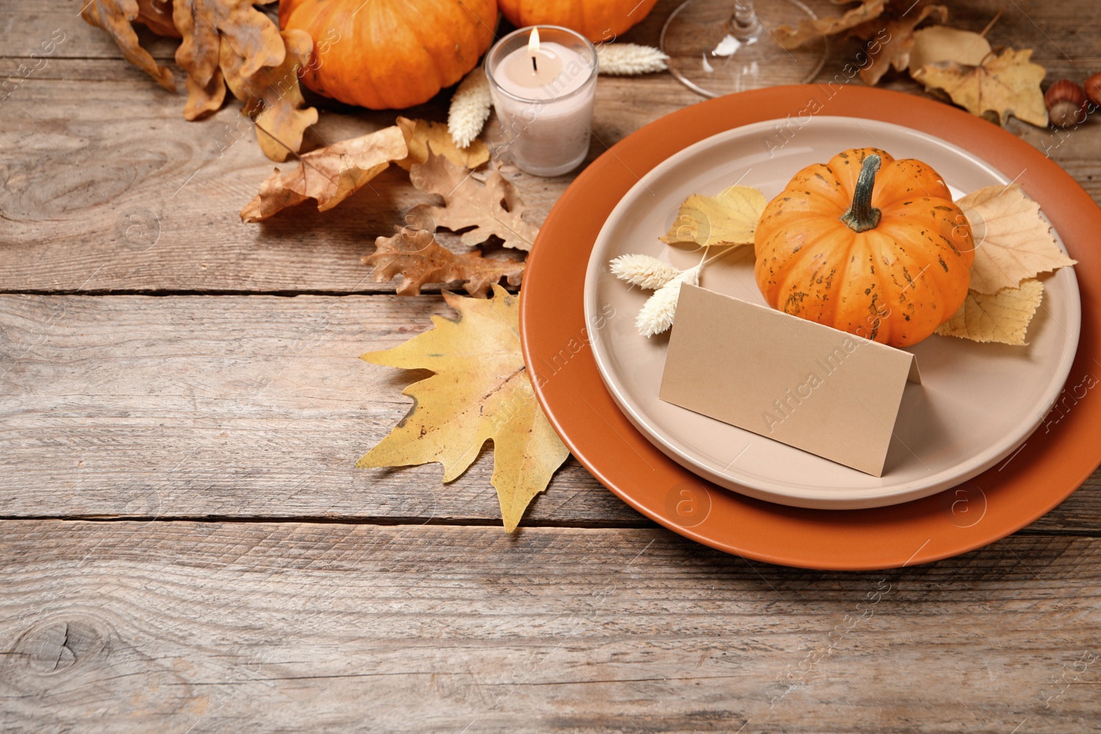 Photo of Beautiful autumn place setting with blank card and decor on wooden table, space for text