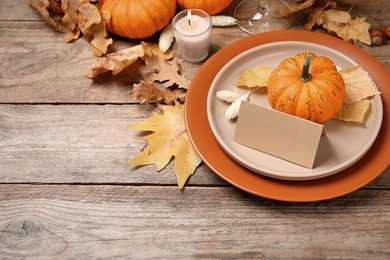 Beautiful autumn place setting with blank card and decor on wooden table, space for text