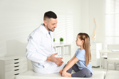 Professional orthopedist examining little girl in clinic