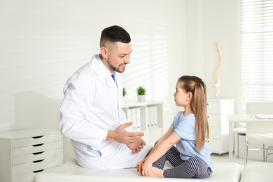 Photo of Professional orthopedist examining little girl in clinic