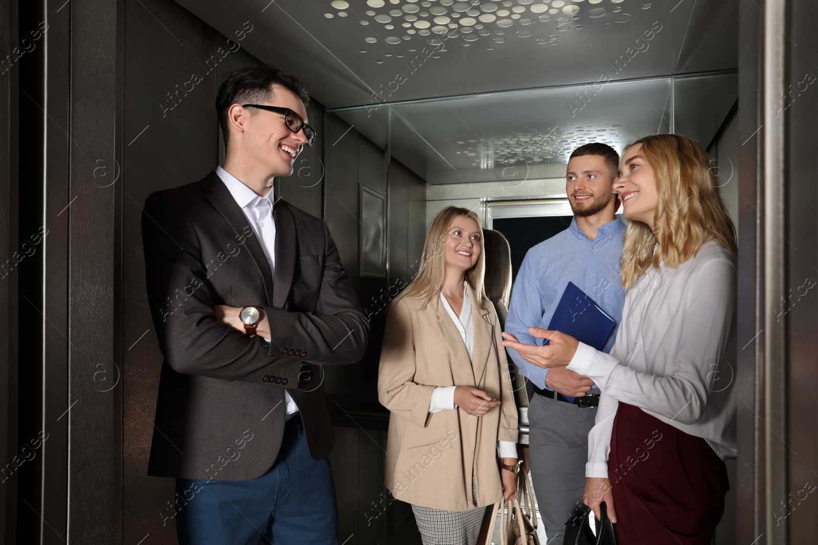 Photo of Group of office workers talking in modern elevator