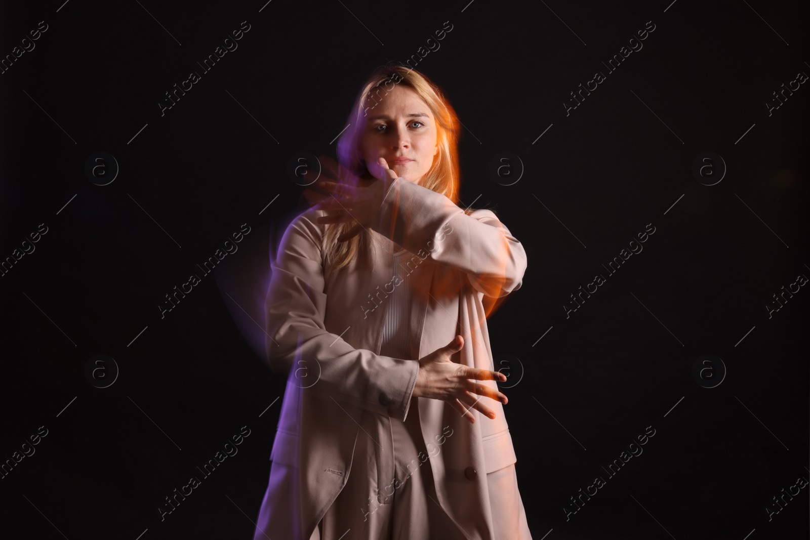 Photo of Young woman performing contemporary dance on black background, motion blur effect